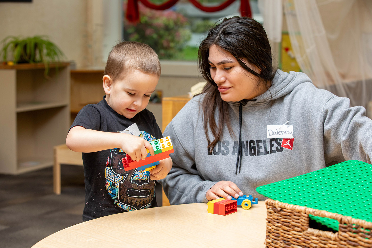 A child plays with building blocks alongside an adult